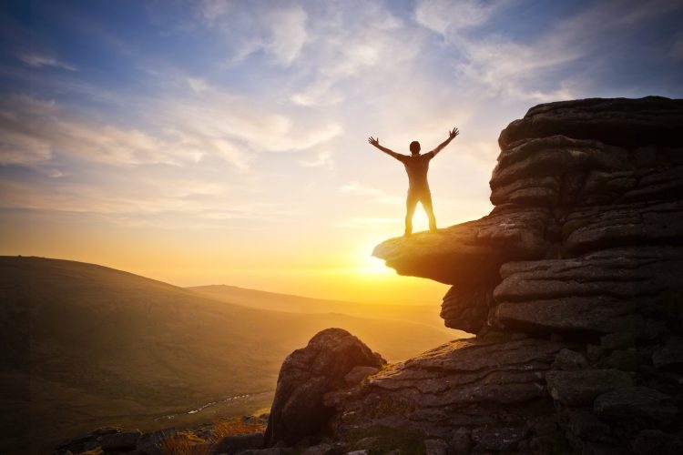 A person expressing freedom - reaching up into the sky against a sunset.